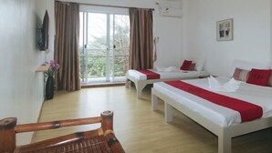 A hotel room with two beds, a wooden chair, a window with curtains, a flat-screen TV, and a small table with a vase. - RedDoorz @ Garvs Boutique Hotel Boracay (Boracay Island)