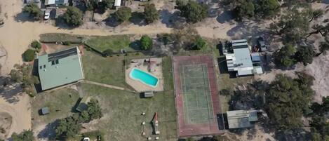 An aerial view of a residential area with houses, a swimming pool, and a sports field.