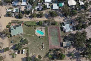 An aerial view of a residential area with houses, a swimming pool, and a sports field. - Roseneath Holiday Park (Meerlieu)
