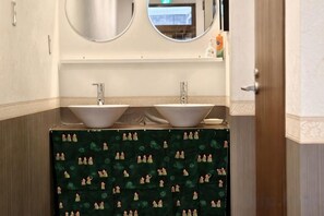 Une salle de bain avec deux lavabos, un miroir au-dessus, et un rideau de douche à motifs.
