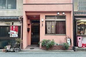 Un edificio con fachada rosa, una entrada visible y una ventana con cortina.