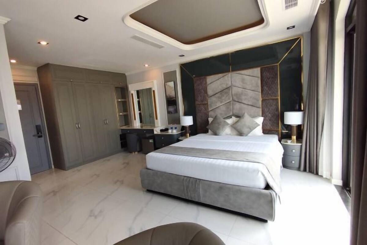 A modern bedroom with a large bed, bedside tables, a wardrobe, and a mirror.