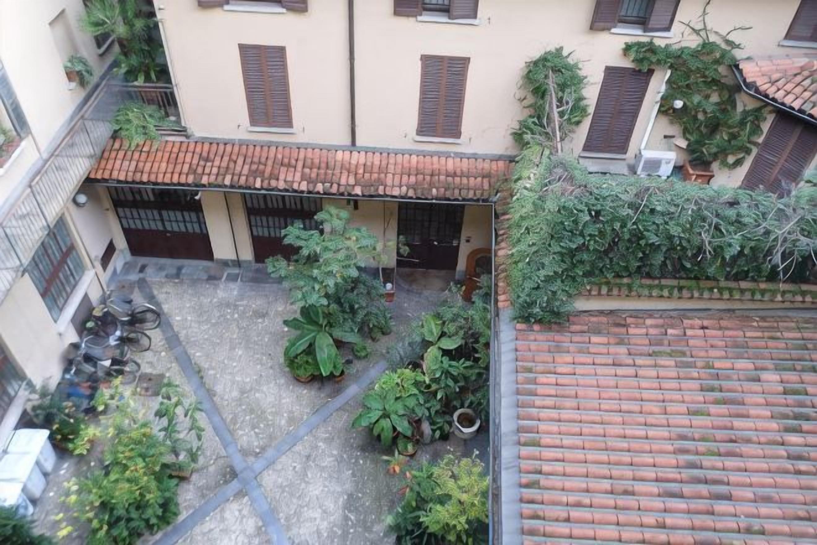A courtyard with a tiled roof, potted plants, and a bicycle.