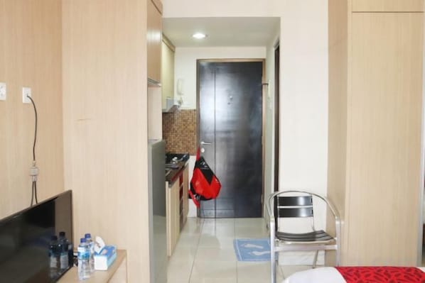 A hotel room with a bed, a TV, a desk with a computer, a chair, and a door leading to a bathroom. - Taman Sari Sudirman Studio Deluxe B / Near MRT / Central Jakarta (South Jakarta)