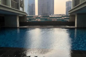 A swimming pool with a view of tall buildings in the background. - Taman Sari Sudirman Studio Deluxe B / Near MRT / Central Jakarta (South Jakarta)