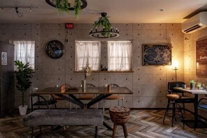 A dining area with a wooden table, chairs, a bench, and a hanging plant.