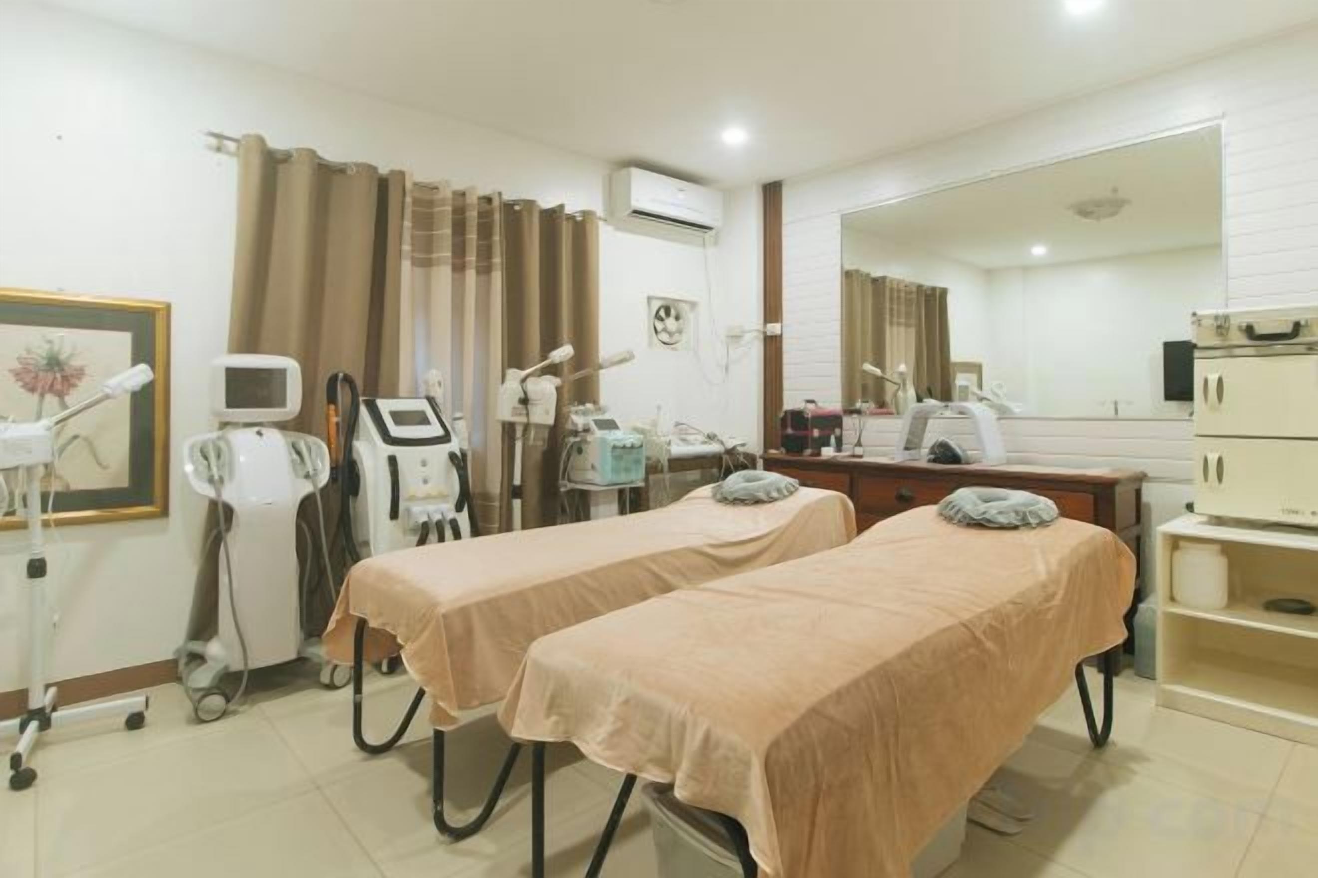 A medical examination room with two examination beds, a desk with a computer, and medical equipment.