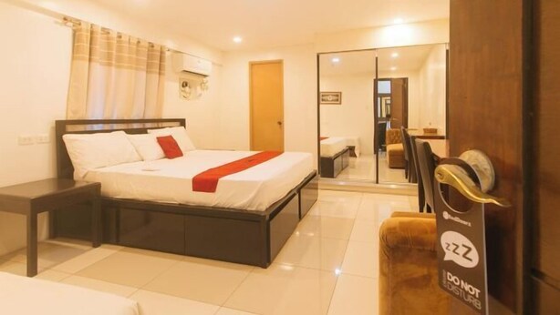 Un dormitorio con cama, mesita de noche y espejo.