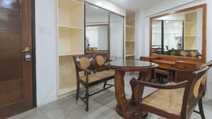 Un comedor con una mesa redonda y cuatro sillas, un espejo grande y estanterías empotradas.