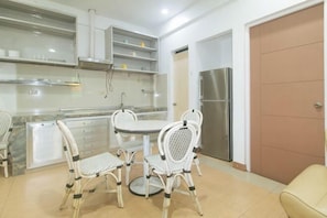 Una cocina moderna con sillas de mimbre blanco, un refrigerador de acero inoxidable y estantes empotrados.