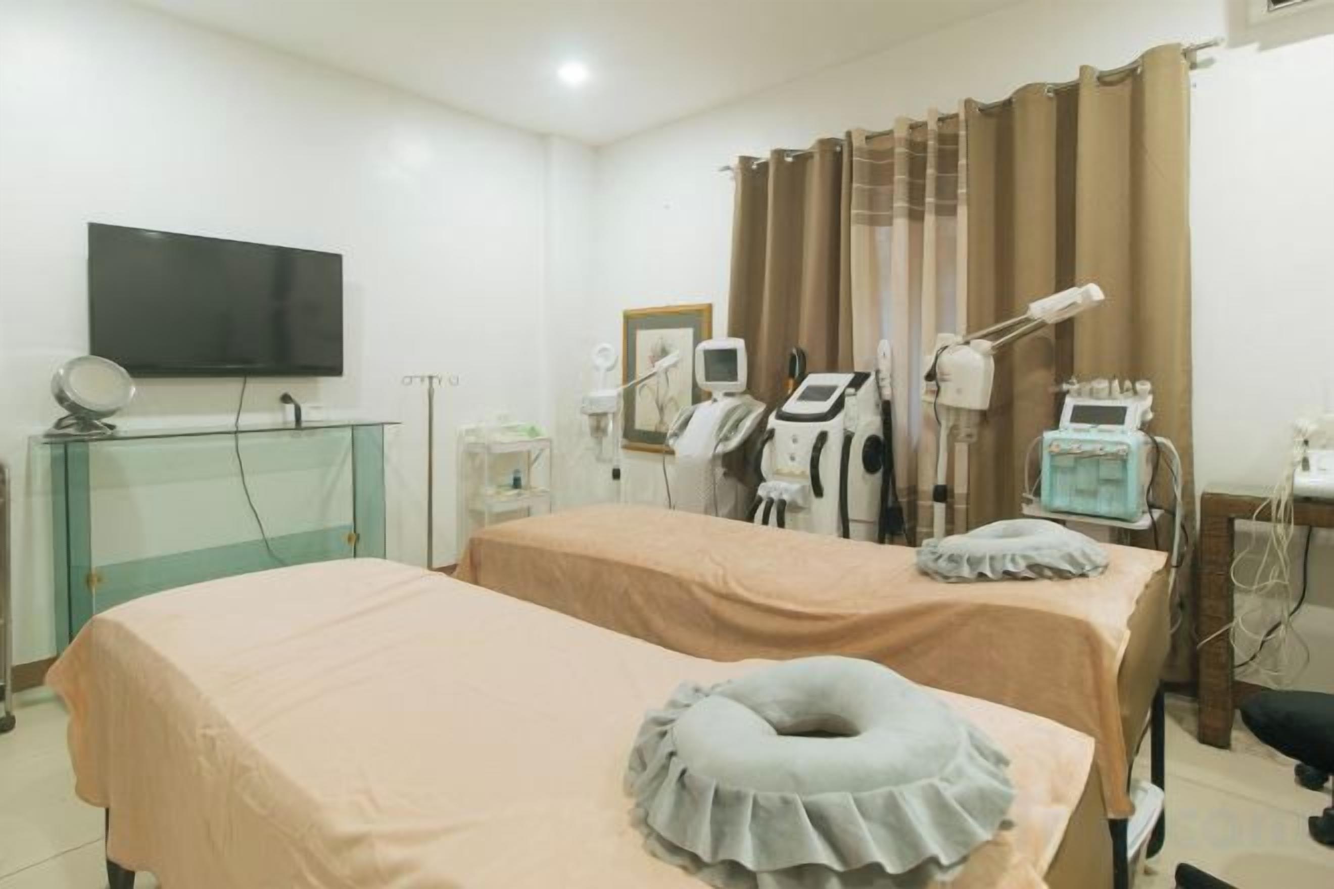 A medical examination room with two beds, a television, and medical equipment.