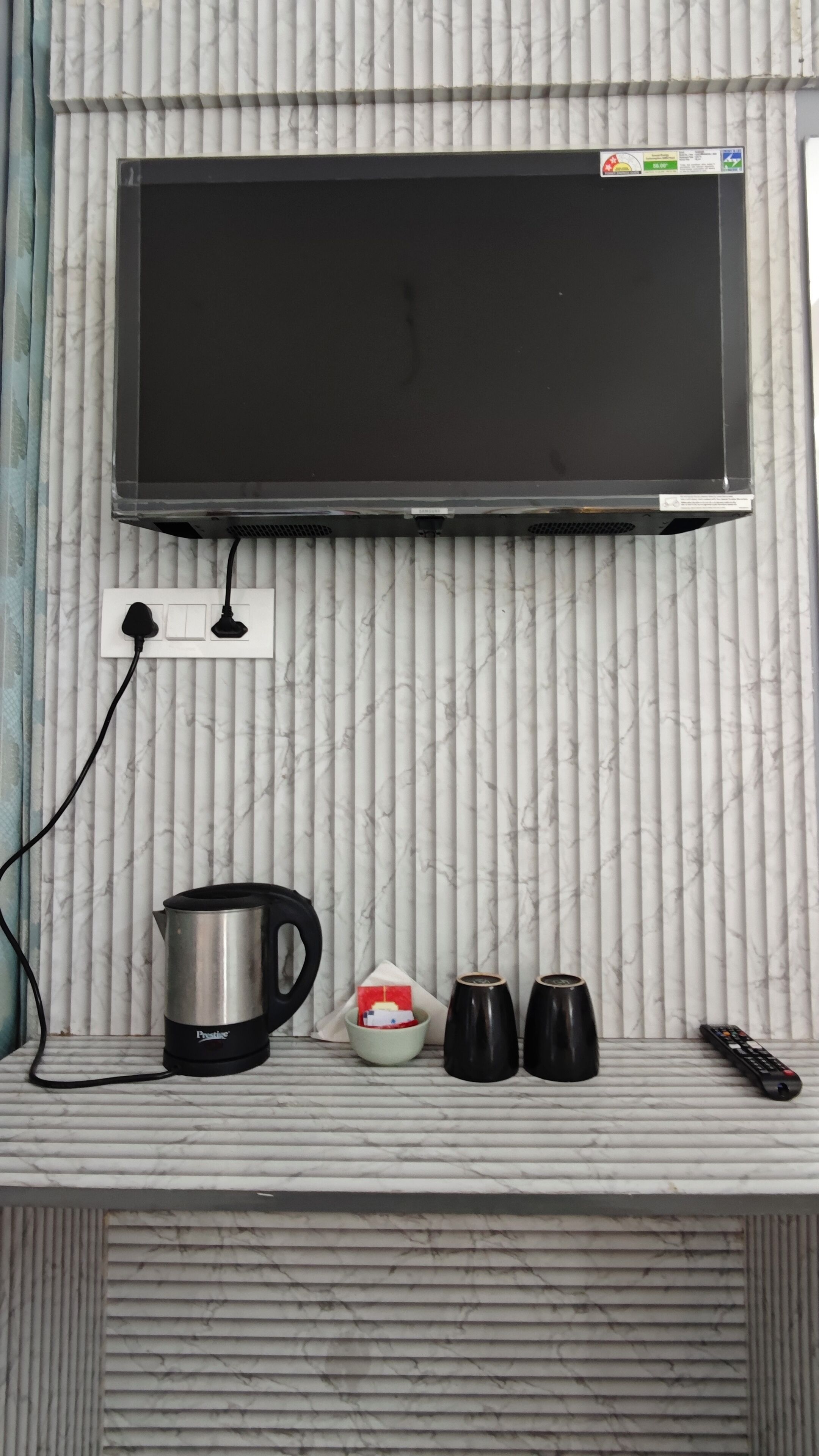 Una cocina con una televisión de pantalla plana sobre una encimera de mármol.
