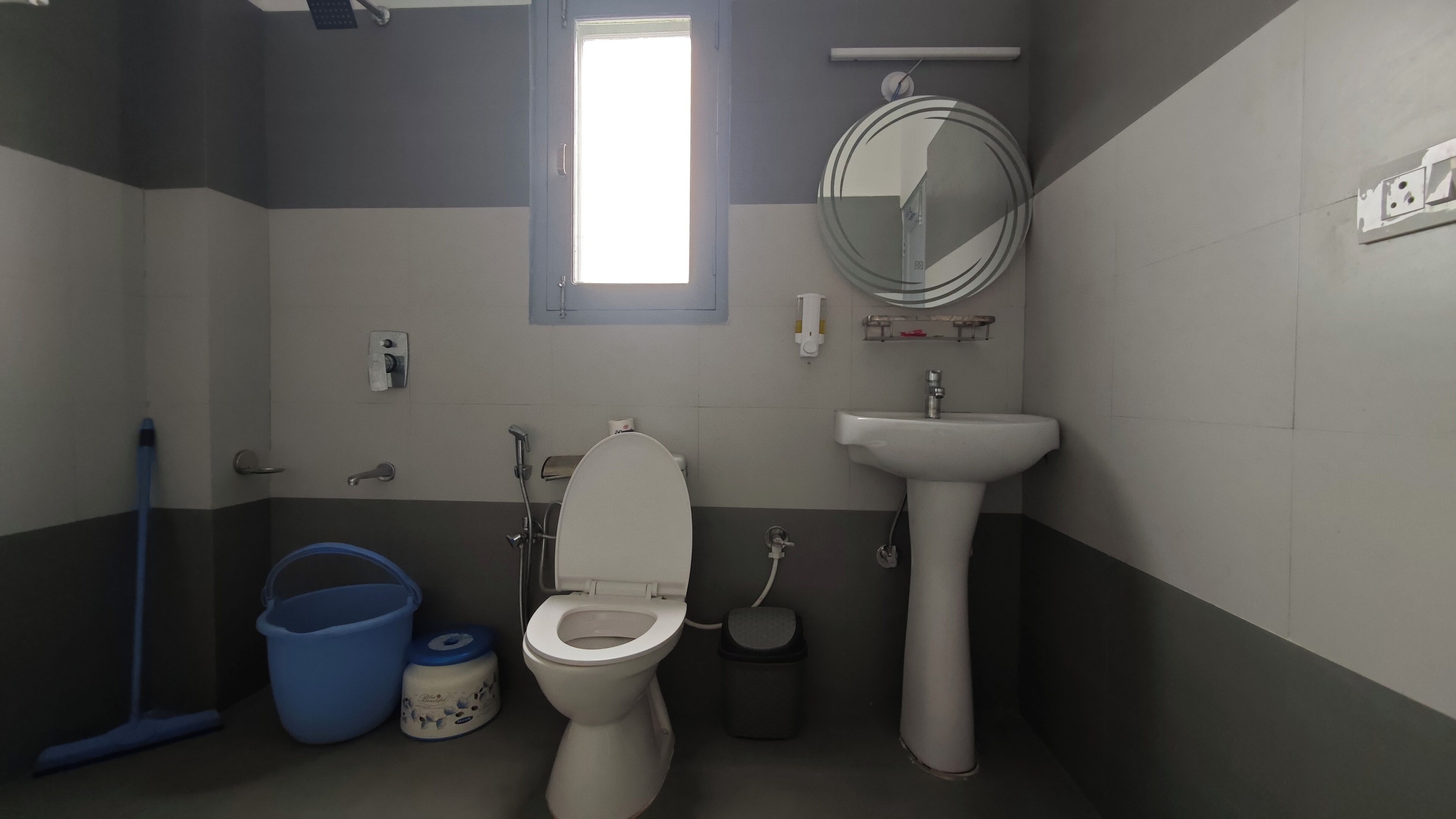 A bathroom with a toilet, sink, and a window.