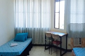 Una habitación con dos camas, un escritorio y una silla.