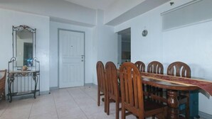 A dining area with a wooden table and chairs, a mirror, and a door. - Winland JY7 Cebu by RedDoorz (Cebu City)