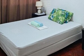 A neatly made bed with a pillow and a rolled towel. - Winland JY7 Cebu by RedDoorz (Cebu City)