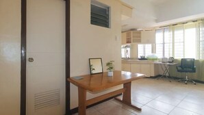 A room with a wooden table, a chair, a small plant, and a window with curtains. - Winland JY7 Cebu by RedDoorz (Cebu City)