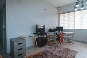 A room with a desk, television, and storage unit. - Winland JY7 Cebu by RedDoorz (Cebu City)