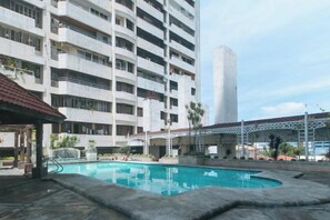 Zona de piscina con un edificio de varios pisos al fondo.