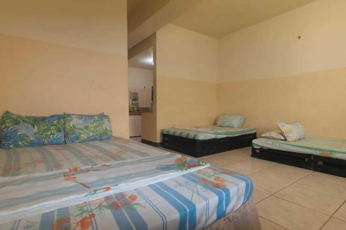 A bedroom with a bed, two smaller beds, and a bathroom visible through an open doorway.