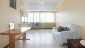 A living room with a sofa, a coffee table, and a dining table. - Winland JY7 Cebu by RedDoorz (Cebu City)