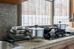 A kitchen with granite countertops, a gas stove, and cookware. - Greta Villa (Pattaya)