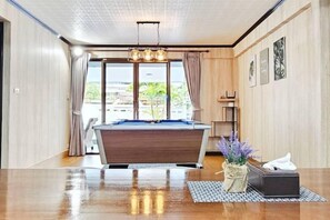 A room with a pool table, a chandelier, and a view of the outdoors. - Greta Villa (Pattaya)