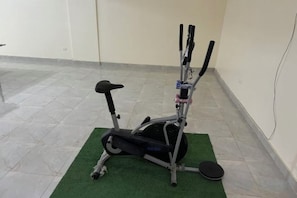 An exercise machine on a green mat in a room with tiled flooring and white walls. - Orange Chinese Hotel (New Cairo City)