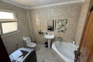 A bathroom with a toilet, sink, and bathtub. - Orange Chinese Hotel (New Cairo City)