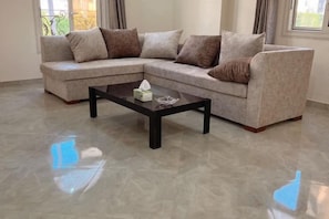 A living room with a sectional sofa, a coffee table, and a large window. - Orange Chinese Hotel (New Cairo City)