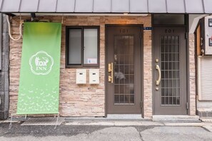Een gebouw met een bruine deur waarop '101' staat en een groene banner met een logo.