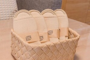 A woven basket containing several beige slippers with a logo on them. - FOXINN (Osaka)