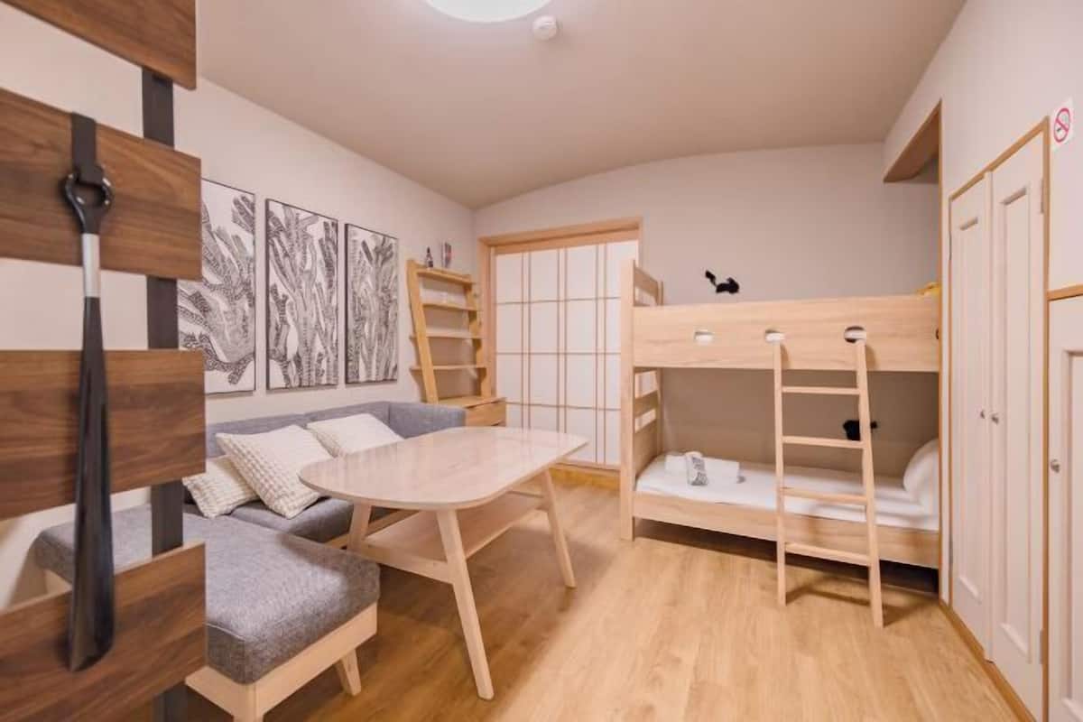 A cozy room with a bunk bed, a sofa, a table, and a wardrobe.