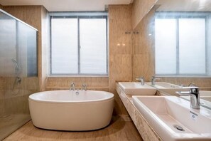 Une salle de bain moderne avec une grande baignoire, deux lavabos et une douche.