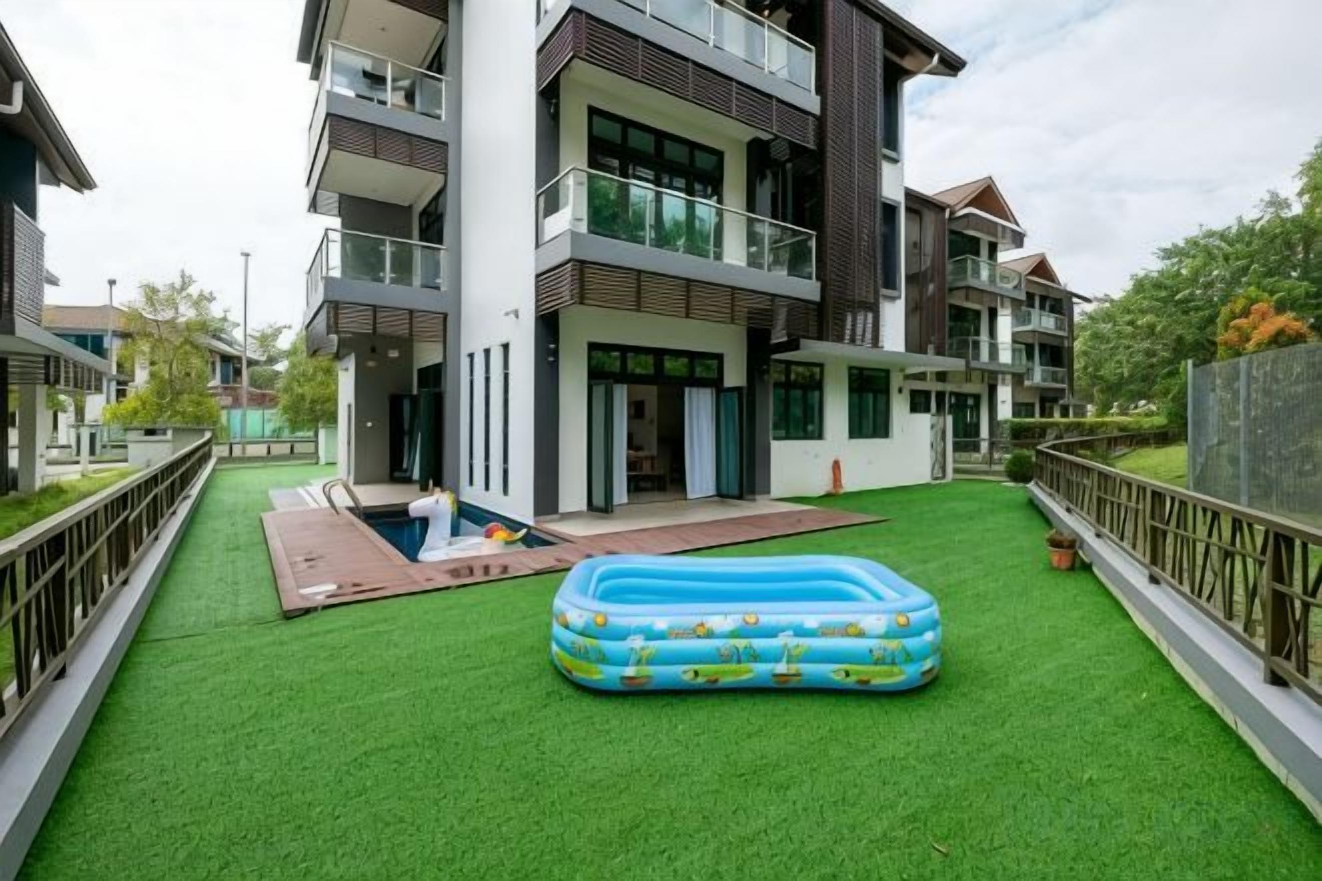 Una zona residencial con piscina, césped verde y un gran inflable para piscina.