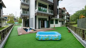 Una zona residencial con piscina, césped verde y un gran inflable para piscina.