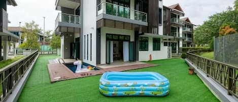 A residential area with a swimming pool, a green lawn, and a large inflatable pool.
