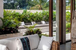 A modern outdoor seating area with a white sofa and wicker chairs, surrounded by lush greenery and a view of a landscaped garden. - Villa Zen Paradise by BaliSuperHost (Bali)