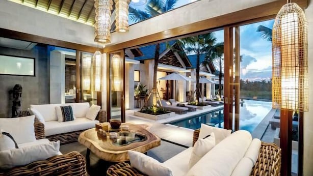 A modern indoor pool area with wicker furniture, large windows, and a view of the pool. - Villa Zen Paradise by BaliSuperHost (Bali)