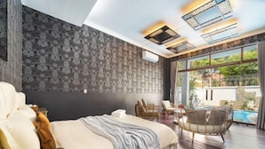 Een slaapkamer met een groot bed, uitzicht op een zwembad en een plafond met dakramen.