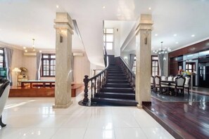 Un intérieur spacieux avec un escalier central, un coin repas et un comptoir d’accueil.