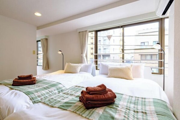 A hotel room with two beds, a large window, and a view of buildings. - Land Forest Ryogoku (Tokyo)