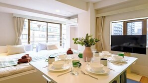 A hotel room with a bed, a dining table set with plates, glasses, and a vase with flowers. - Land Forest Ryogoku (Tokyo)