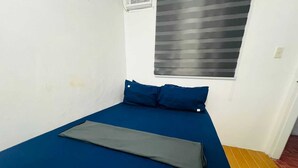 A small, single-bed room with a blue mattress, two blue pillows, and a grey blanket. - T&A Building  (Pasay)