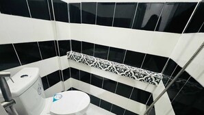 A small, modern bathroom with a toilet, a shower, and a patterned tile backsplash. - T&A Building  (Pasay)