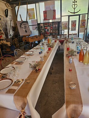 A long dining table set with glassware, plates, and bottles, surrounded by chairs and a rustic decor. - Guest Room "Little Boudha Room" with Shared Terrace, Wi-Fi, and Air Conditioning (Bernis)
