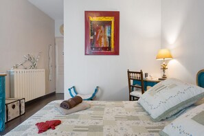 A bedroom with a bed, a chair, a table, a lamp, a radiator, and a painting on the wall. - Guest Room "Little Boudha Room" with Shared Terrace, Wi-Fi, and Air Conditioning (Bernis)