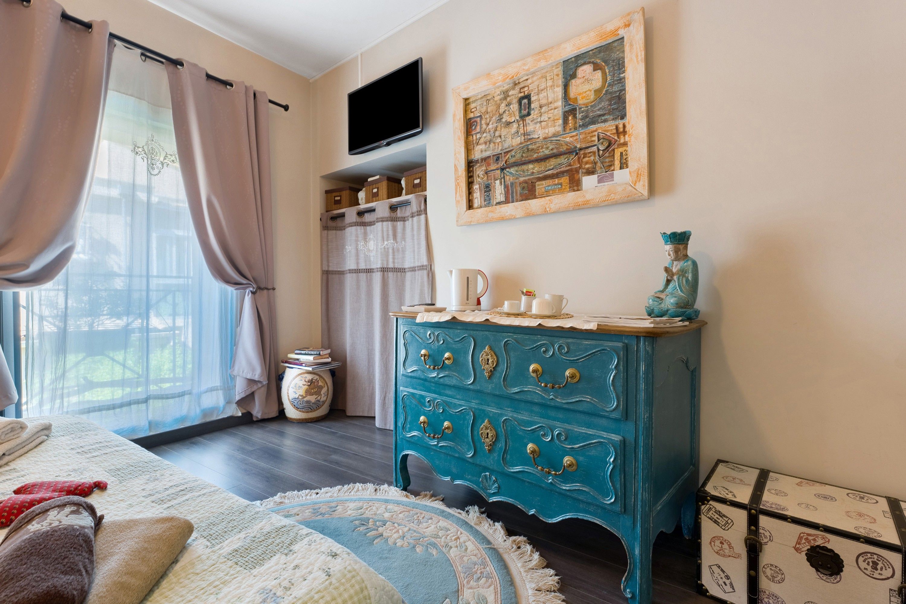 Una habitación con una cama, un aparador, un televisor y una ventana con cortinas.