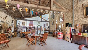A rustic interior with a wooden table and chairs, a stone wall, and various decorations. - Guest Room "Little Boudha Room" with Shared Terrace, Wi-Fi, and Air Conditioning (Bernis)