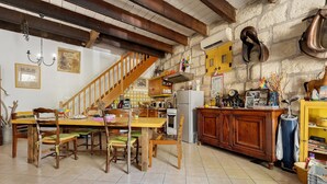 A rustic kitchen with a wooden staircase, a dining table with chairs, and a variety of kitchen appliances and decorations. - Guest Room "Little Boudha Room" with Shared Terrace, Wi-Fi, and Air Conditioning (Bernis)
